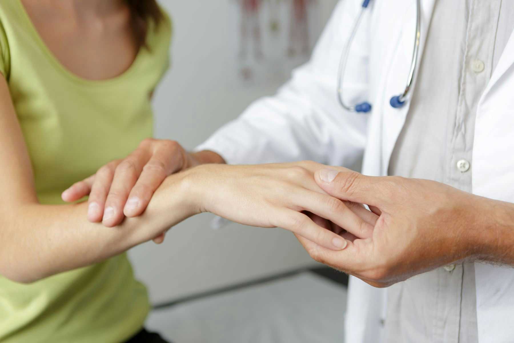 Doctor inspecting female patient wrist