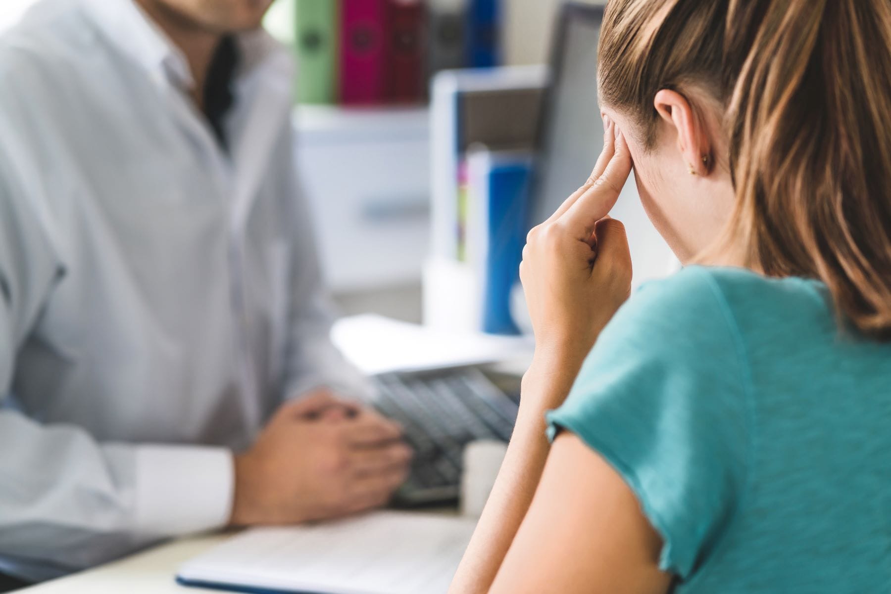 Woman suffering from bad headache or migraine. Appointment with doctor in office room.