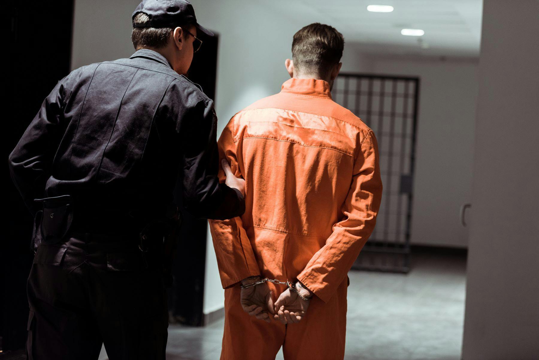 Corrections officer leading prisoner down hallway