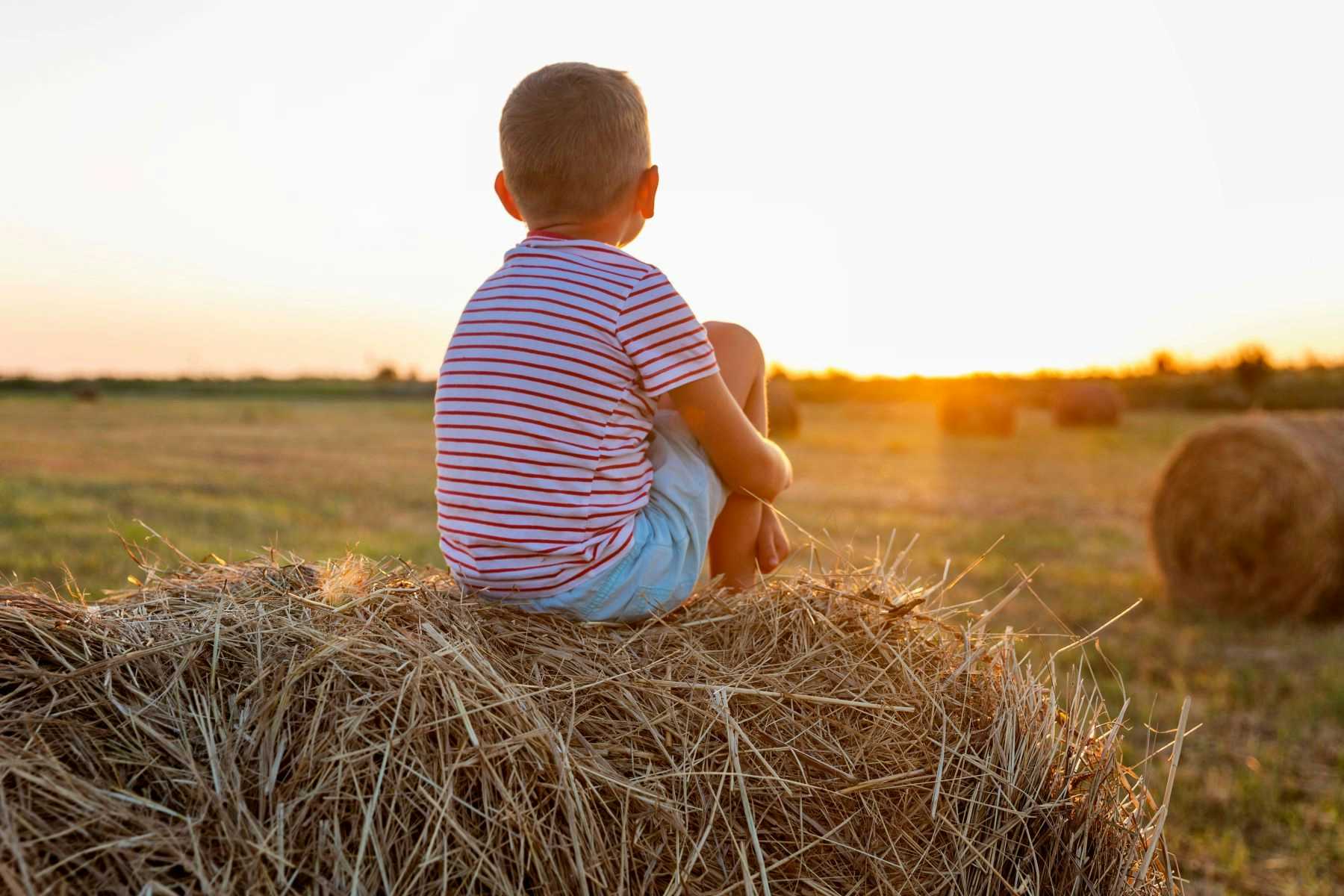 Child sitting on hay bale