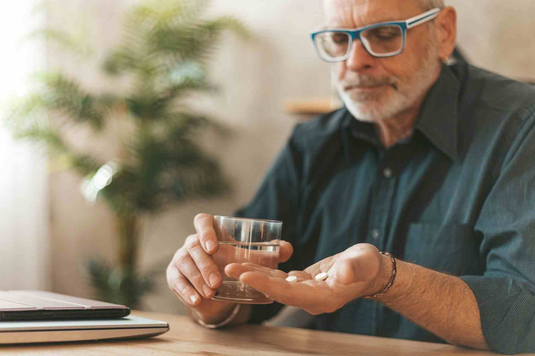 Adult man taking pills with water