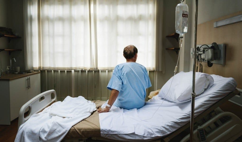 older man sitting up in hospital bed
